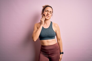 Young beautiful blonde sportswoman doing sport wearing sportswear over pink background touching mouth with hand with painful expression because of toothache or dental illness on teeth. Dentist