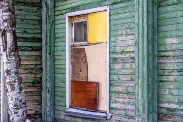 An old abandoned wooden house with a boarded-up window.