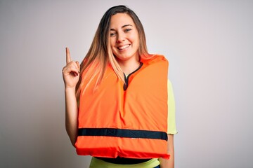 Young beautiful blonde woman with blue eyes wearing orange lifejacket over white background...