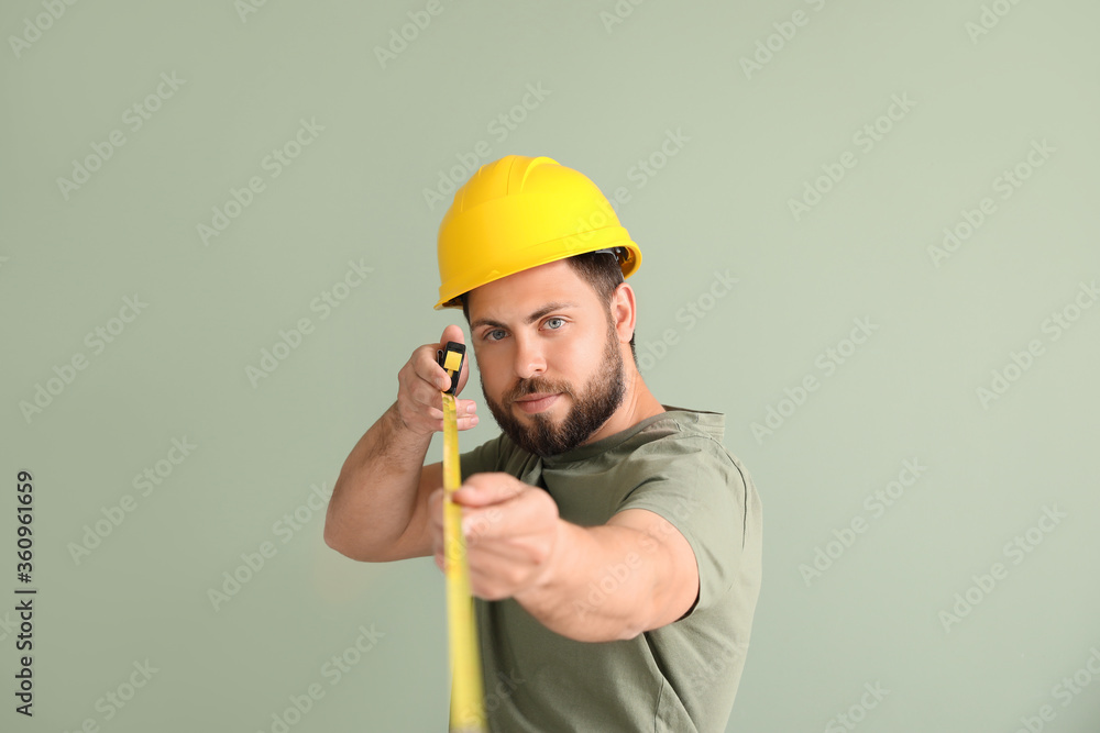 Wall mural male worker with tape measure on color background