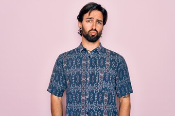 Young handsome hispanic bohemian man wearing hippie style over pink background looking at the camera blowing a kiss on air being lovely and sexy. Love expression.