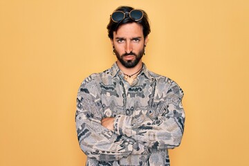 Young handsome hispanic bohemian man wearing hippie style and sunglasses skeptic and nervous, disapproving expression on face with crossed arms. Negative person.
