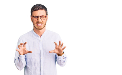 Handsome young man with bear wearing elegant business shirt and glasses smiling funny doing claw gesture as cat, aggressive and sexy expression