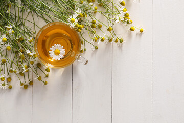 Cup of chamomile tea on white wooden background