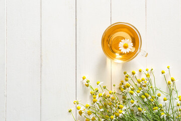 Cup of chamomile tea on white wooden background
