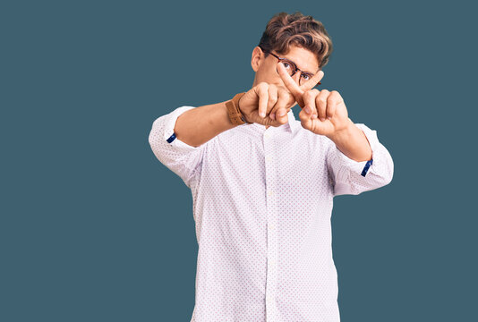 Young handsome man wearing business clothes and glasses rejection expression crossing fingers doing negative sign