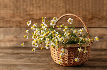 Fototapeta na wymiar Basket with chamomile flowers on wooden background