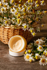 Cosmetic cream chamomile flowers on wooden background
