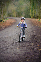 Naklejka premium A young girl rides a bike along a country track towards the camera