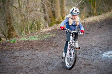 Naklejka premium A young girl riding a bike along a country track