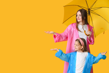 Mother and little daughter with umbrella on color background