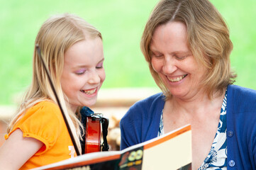 Very happy mother and daughter learning to play violin
