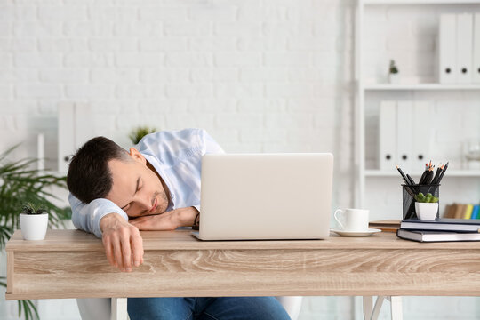 Young man falling asleep during work in office. Concept of sleep deprivation
