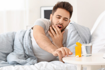 Obraz na płótnie Canvas Man taking sleeping pills from table in bedroom