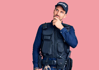 Young handsome man wearing police uniform with hand on chin thinking about question, pensive...