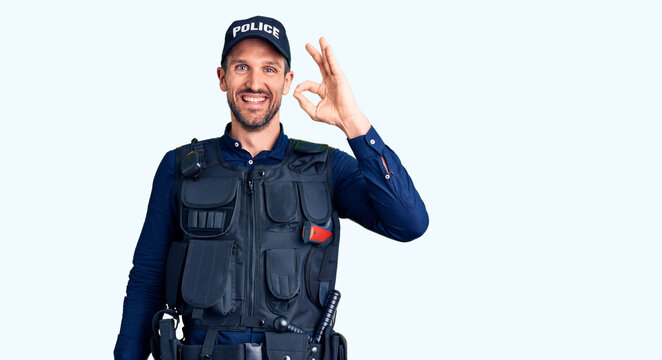 Young handsome man wearing police uniform smiling positive doing ok sign with hand and fingers. successful expression.