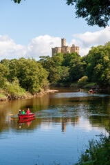 Rowing boats on the River Coquet with Warkworth Castle in the background on a sunny day