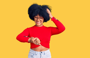 Young african american girl wearing casual clothes and glasses looking at the watch time worried,...