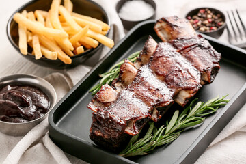 Tasty beef short ribs with sauce and french fries on table