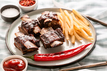 Tasty beef short ribs with sauce, chili pepper and french fries on table