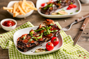 Tasty beef short ribs with vegetables on table