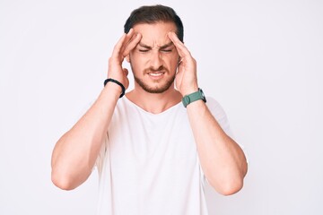 Young handsome man wearing casual white tshirt with hand on head for pain in head because stress....