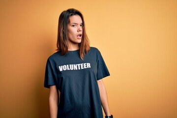 Young beautiful brunette girl doing volunteering wearing t-shirt with volunteer message word In...