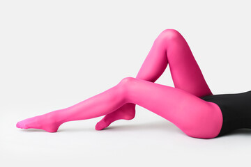 Beautiful young woman in tights on light background