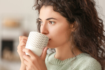 Beautiful young woman drinking hot tea at home