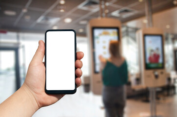 A mockup of a smartphone with a white screen close-up in a person hand, against the background of a restaurant and electronic menu with people.