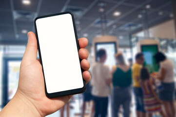A mockup of a smartphone with a white screen close-up in a person hand, against the background of a restaurant and electronic menu with people.