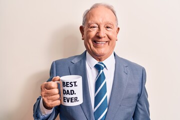 Handsome grey-haired man wearing suit drinking cup of coffee with best dad ever message looking...