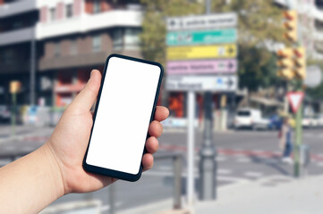 Mockup of the smartphone in the man hand, with a white screen on the background of urban buildings and street signs. Template for mobile navigation application.
