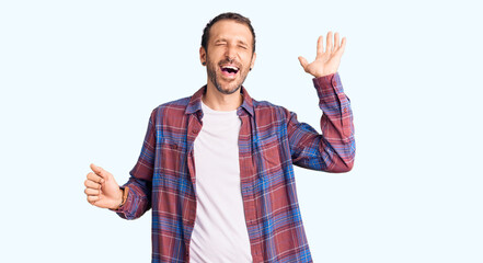 Fototapeta premium Young handsome man wearing casual clothes dancing happy and cheerful, smiling moving casual and confident listening to music