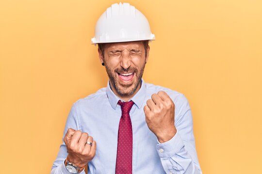 Young handsome man wearing architect hardhat celebrating surprised and amazed for success with arms raised and eyes closed