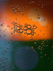 Closeup golden yellow bubbles oil in water with green orange light , blurred abstract background, macro image ,droplets for card design