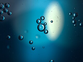 Closeup bubbles oil in water with blue light blurred abstract background, macro image ,droplets for card design	