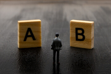 Miniature figurine posed as businessman making decision on Solution A versus B, minimalist abstract...