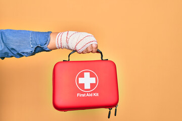 Wounded hand of caucasian young woman cover with bandage holding first aid kit briefcase over...
