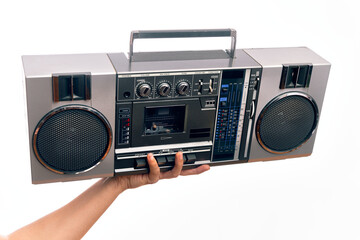 Hand of caucasian young man holding vintage radio cassette over isolated white background