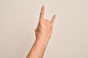 Hand of caucasian young man showing fingers over isolated white background gesturing rock and roll symbol, showing obscene horns gesture