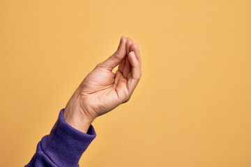 Hand of caucasian young man showing fingers over isolated yellow background doing Italian gesture with fingers together, communication gesture movement