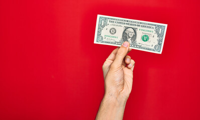 Beautiful hand of man holding one dollar banknote over isolated red background