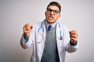 Young doctor man with blue eyes wearing medical coat and stethoscope over isolated background Shouting frustrated with rage, hands trying to strangle, yelling mad