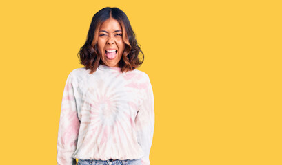 Obraz premium Young beautiful mixed race woman wearing casual tie dye sweatshirt sticking tongue out happy with funny expression. emotion concept.