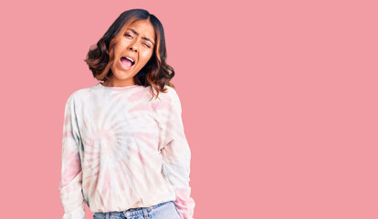 Young beautiful mixed race woman wearing casual tie dye sweatshirt winking looking at the camera with sexy expression, cheerful and happy face.