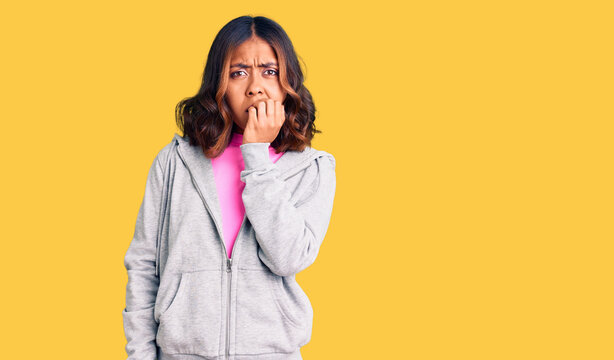 Young beautiful mixed race woman wearing casual sporty clothes looking stressed and nervous with hands on mouth biting nails. anxiety problem.