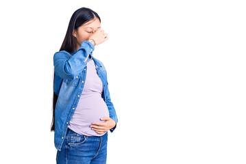 Young beautiful chinese woman pregnant expecting baby tired rubbing nose and eyes feeling fatigue and headache. stress and frustration concept.