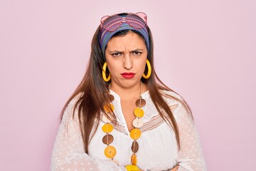 Young hispanic hippie woman wearing fashion boho style and sunglasses over pink background skeptic...