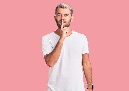 Young handsome blond man wearing casual t-shirt shouting and screaming loud to side with hand on mouth. communication concept.